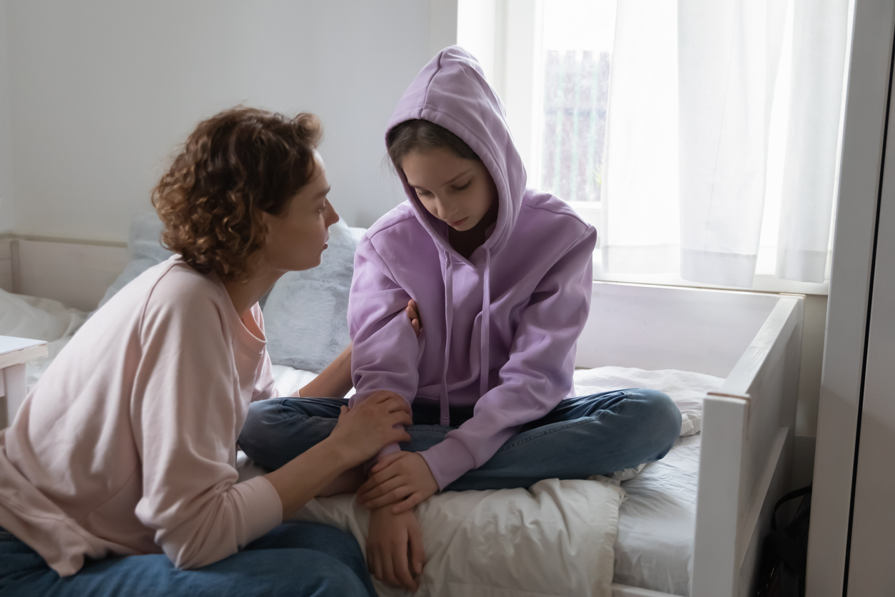 mom talking to sad teenaged daughter