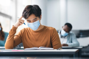 teen boy wearing mask in classroom