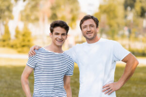 teen boy stands with father