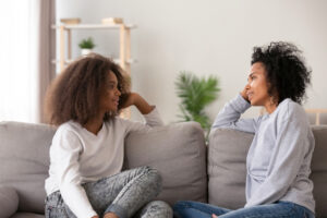 teen girl and mother talk on couch